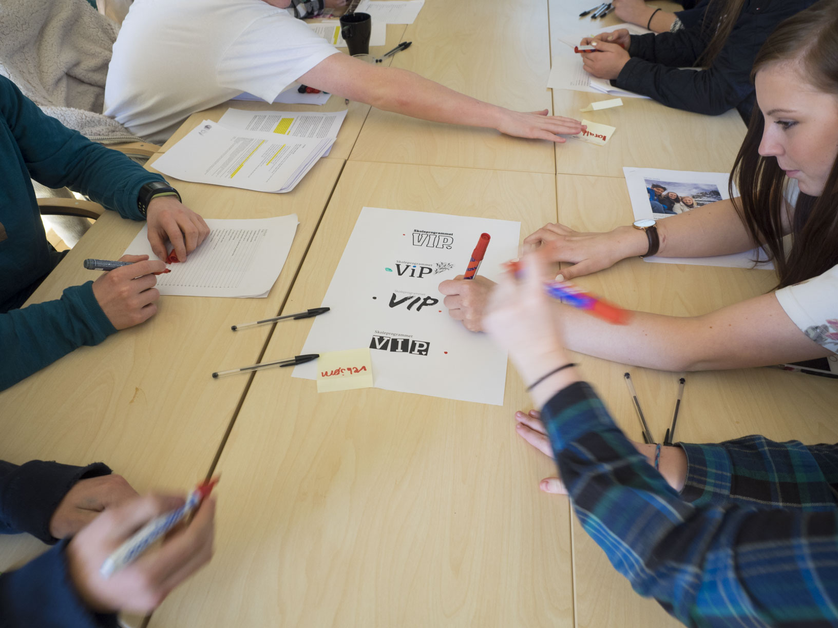 En gruppe mennesker som sitter rundt et bord med papirer på