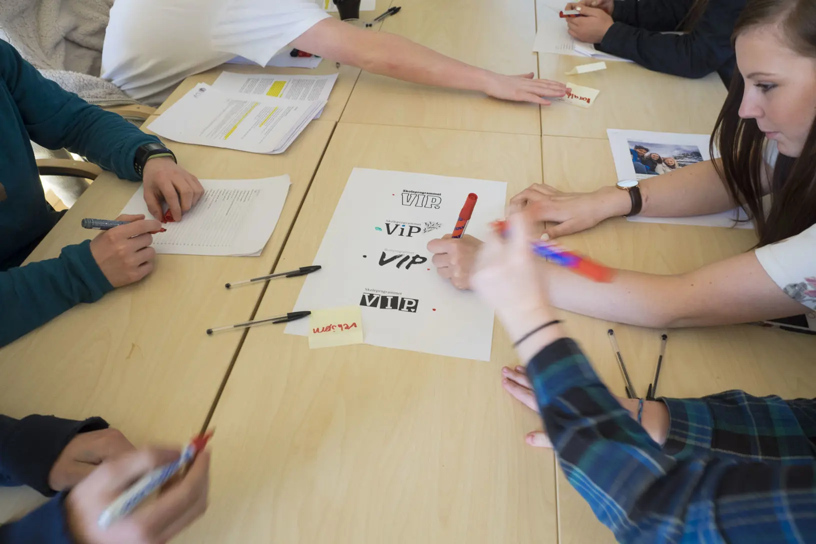En gruppe mennesker som sitter rundt et bord med papirer på
