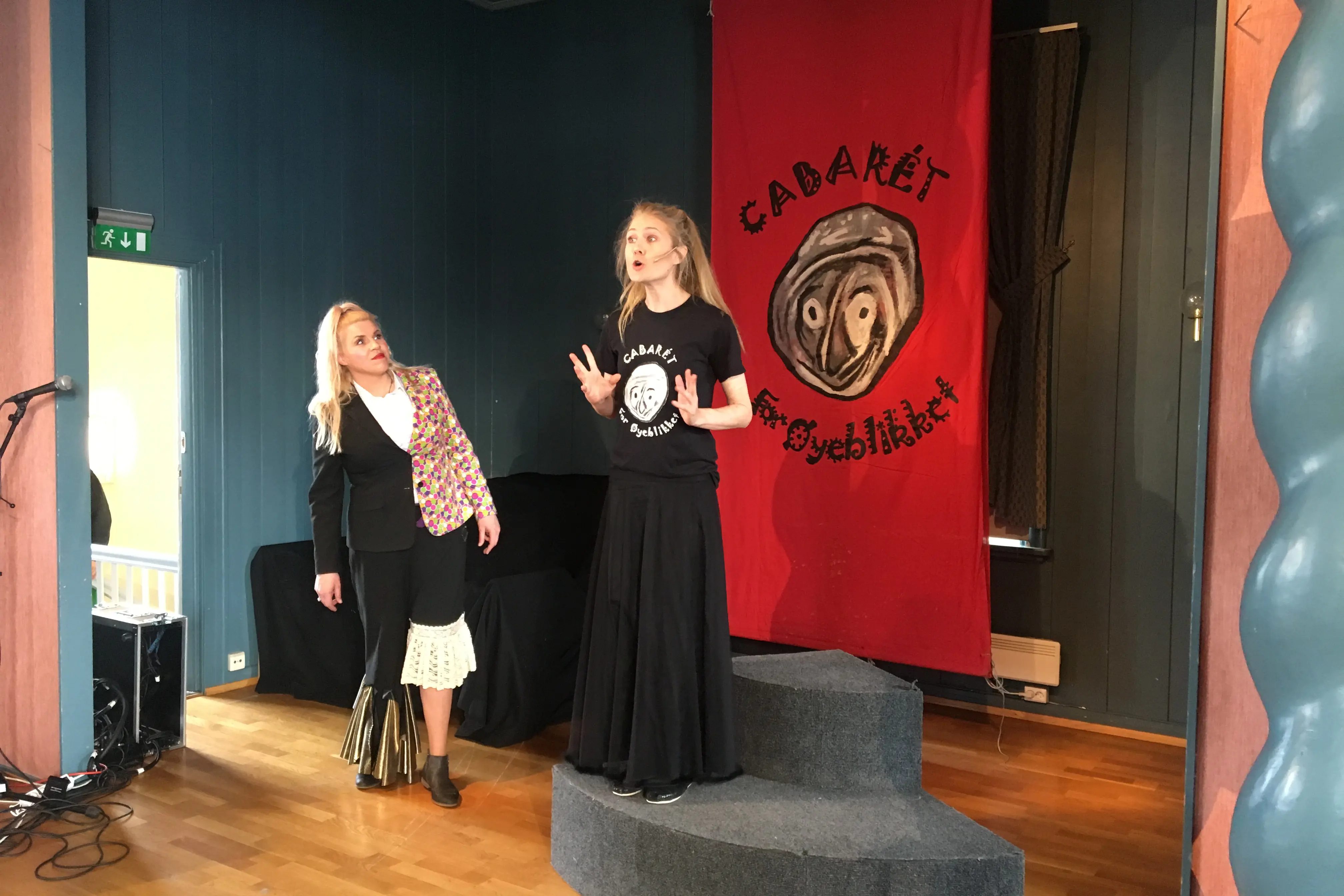 Et par kvinner som står ved siden av et podium med et rødt banner