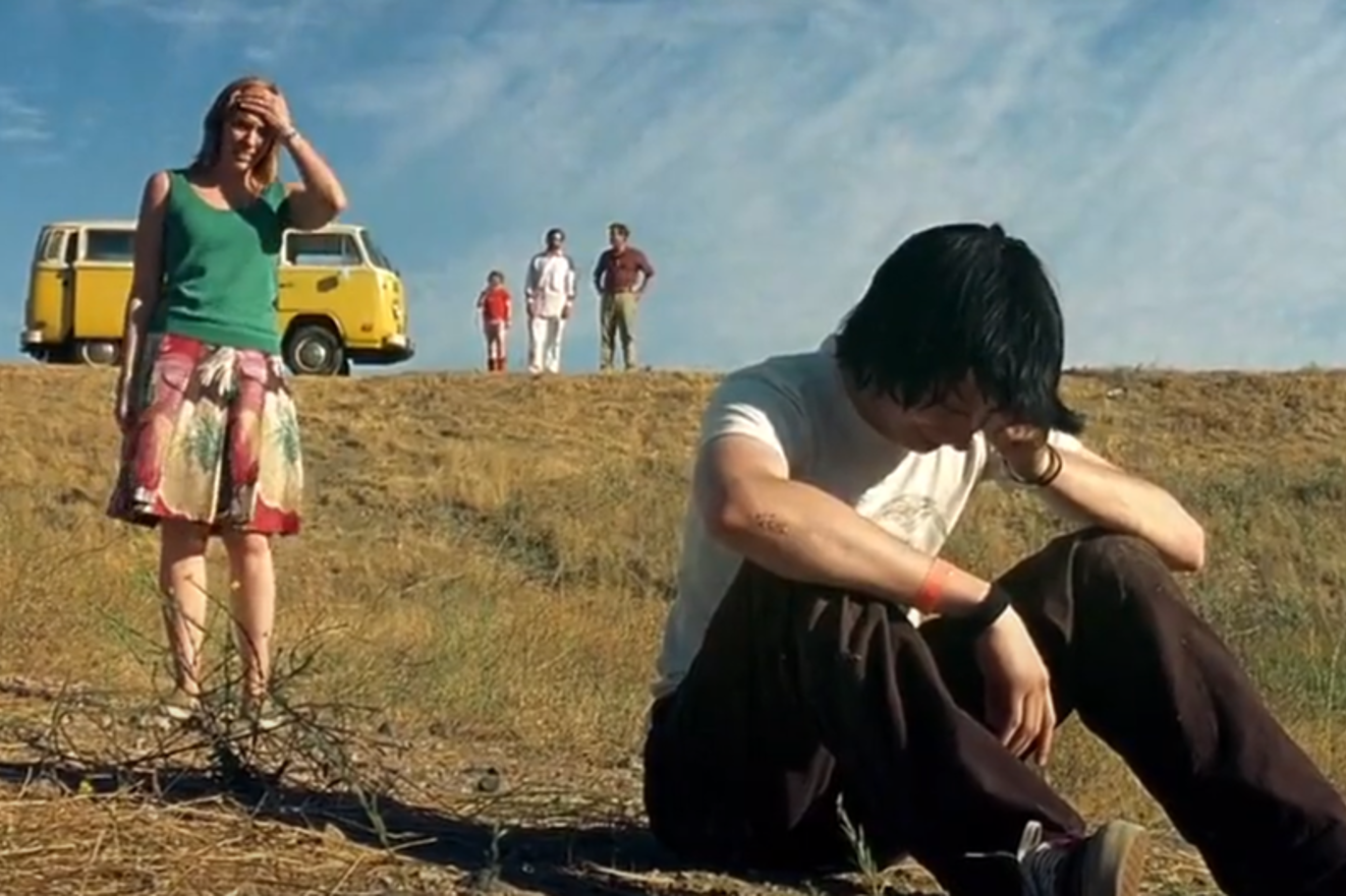 Bilde fra filmen, en ung gutt med cap sitter i veikanten og ser trist ut, mor står bak og ser fortvilet ut.