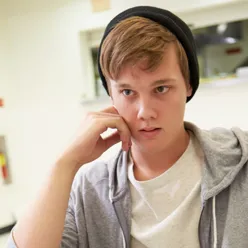 Ung elev med cap snakker med en voksen man ser bakhodet til