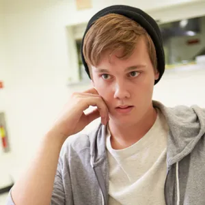 Ung elev med cap snakker med en voksen man ser bakhodet til