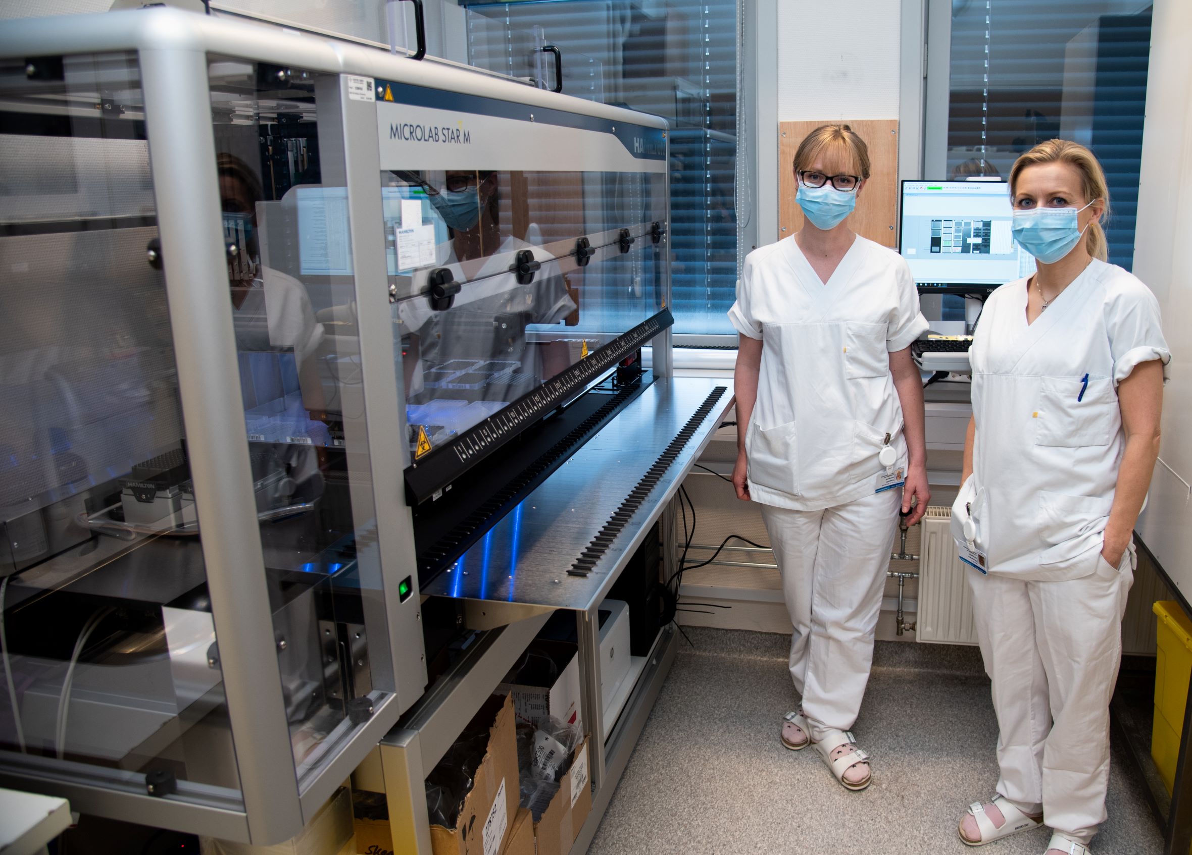 To kvinnelige ansatte med munnbind ved laboratoriet på sykehuset