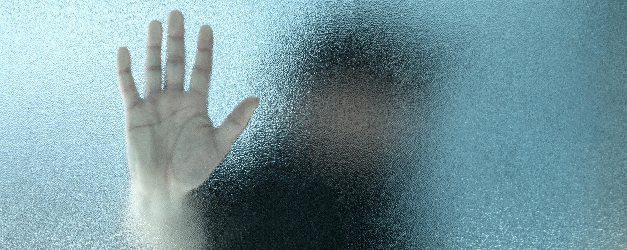 En difus person bak frostet glass, men en hånd på glasset.