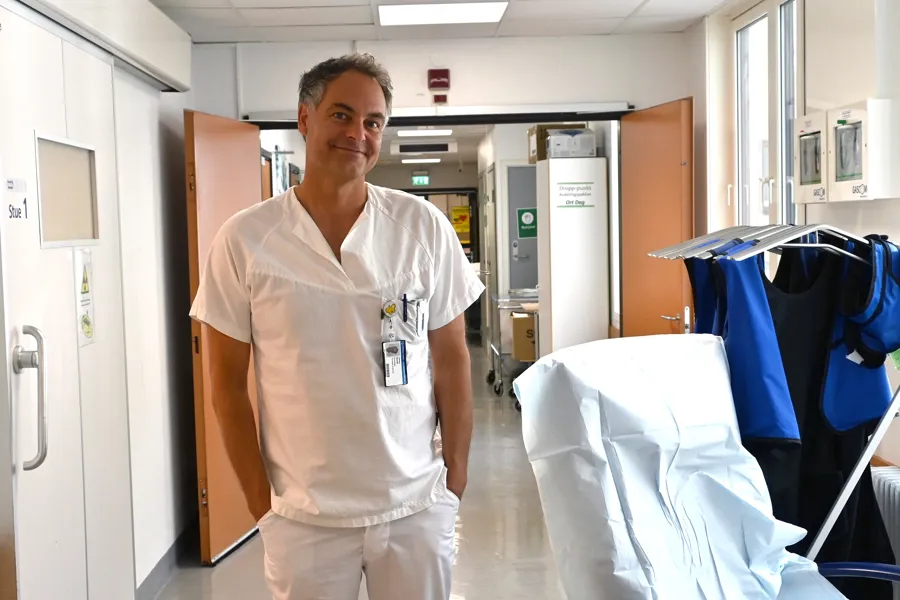 En mann som står ved siden av en sykehusseng