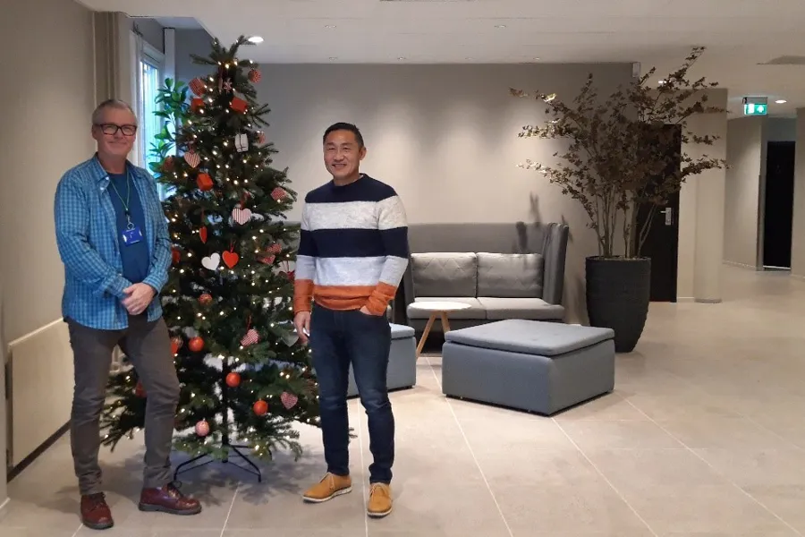 To menn som står ved siden av et juletre