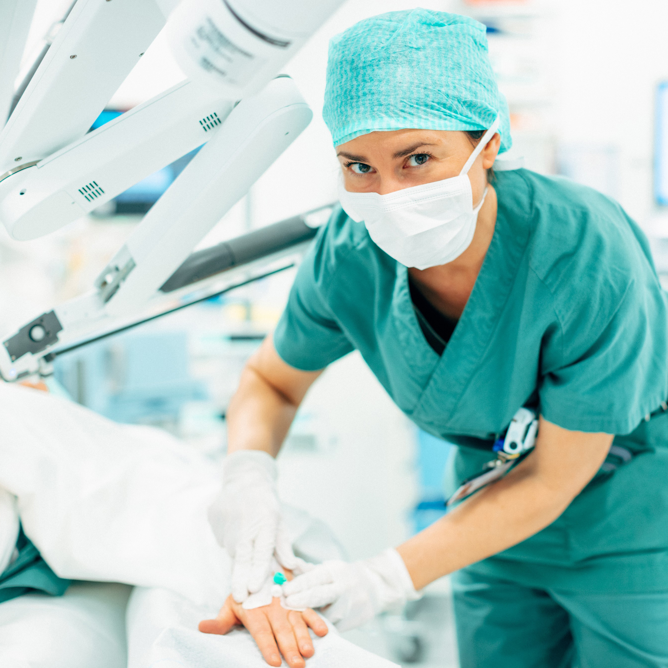 En person i kirurgiske skrubb og en maske som holder en sprøyte