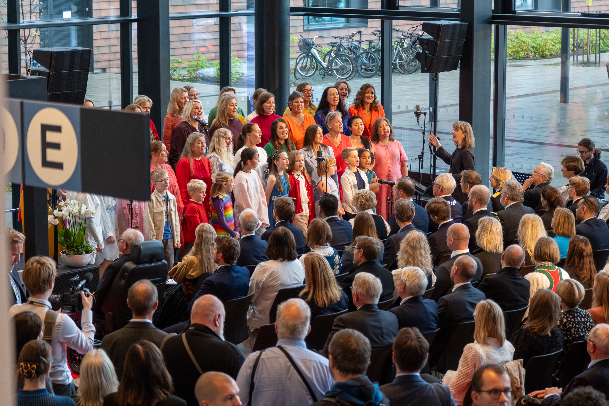 En gruppe mennesker som står i et rom med en scene og en folkemengde