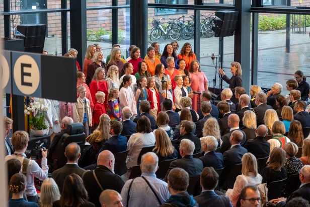 En gruppe mennesker som står i et rom med en scene og en folkemengde