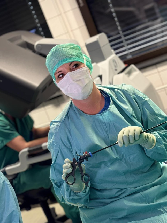 En person i kirurgisk skrubb og en maske som holder en sprøyte