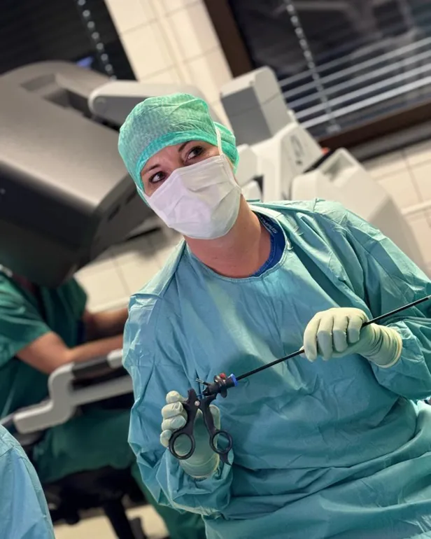 En person i kirurgisk skrubb og en maske som holder en sprøyte