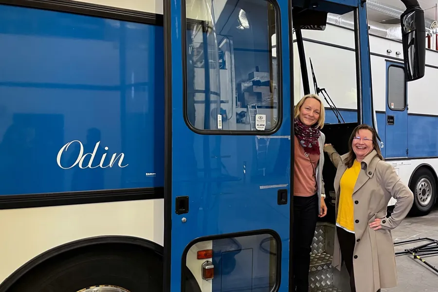 Kvinner som står foran en blå buss