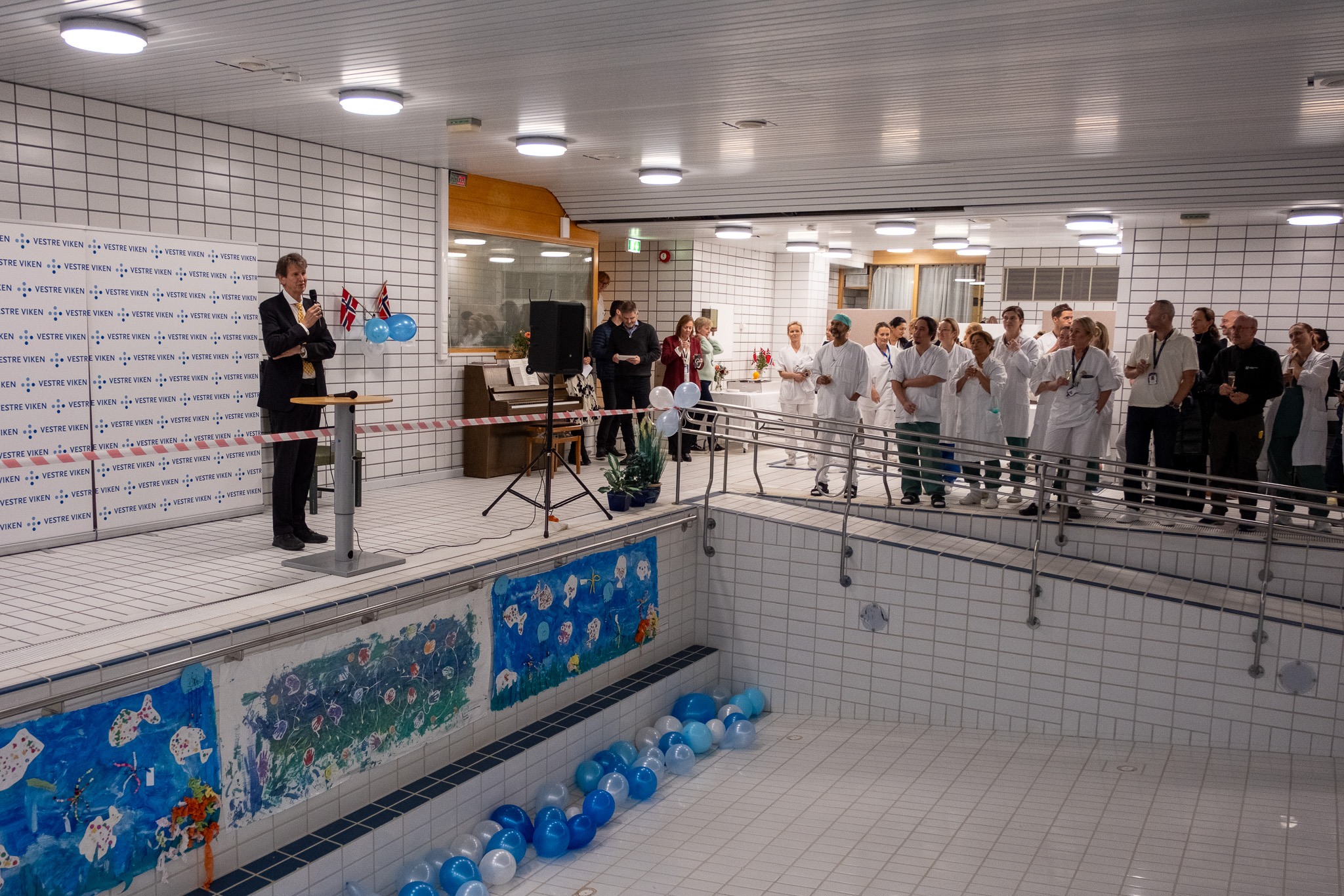 En gruppe mennesker som står i et rom med basseng