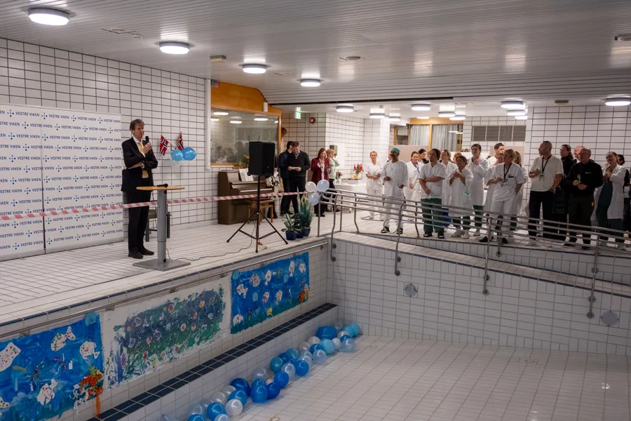 En gruppe mennesker som står i et rom med basseng