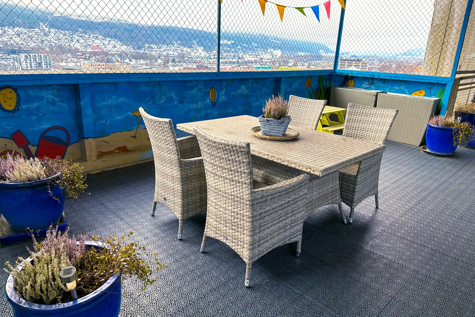 Et bord med stoler og planter på det ved et gjerde og en vannmasse