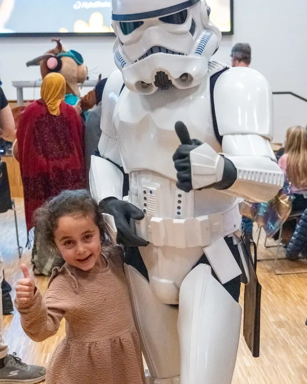 En jente som står ved siden av en person i et plagg