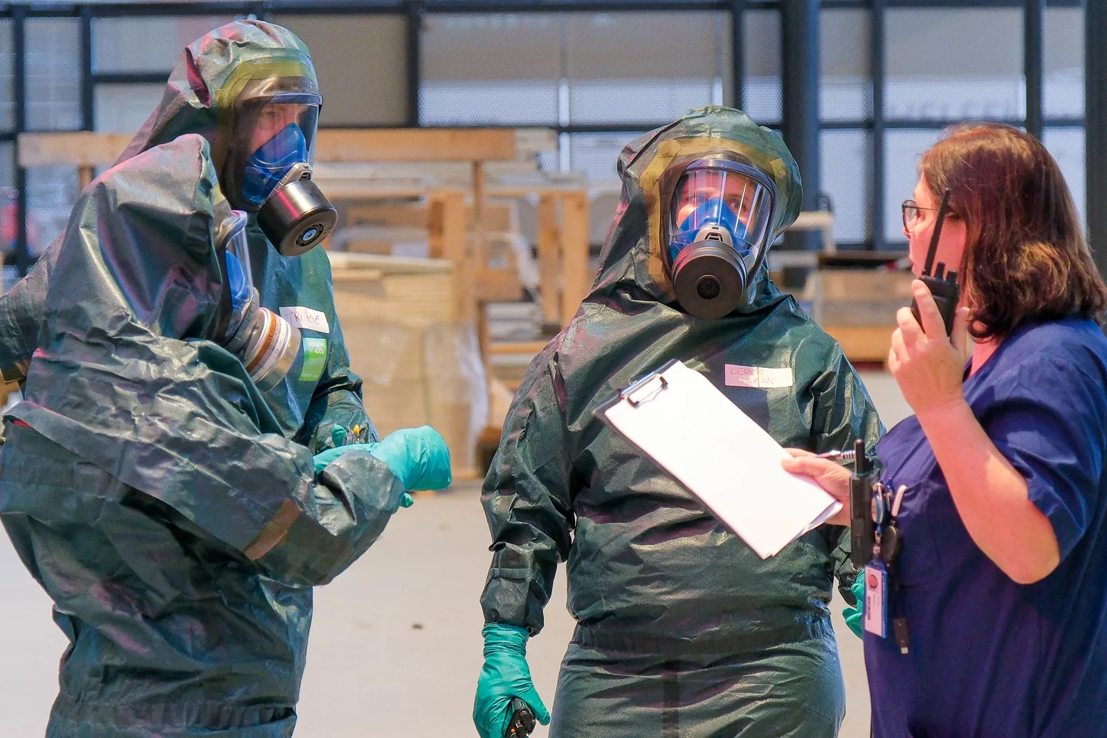 To personer i vernedrakt snakker med person som holder sjekkliste.